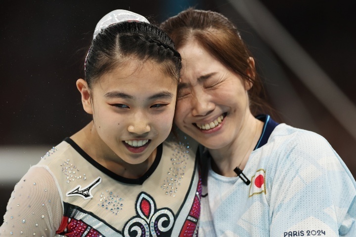 段違い平行棒の演技を終えた岸里奈（左）にコーチはハグした。(C) Getty Images