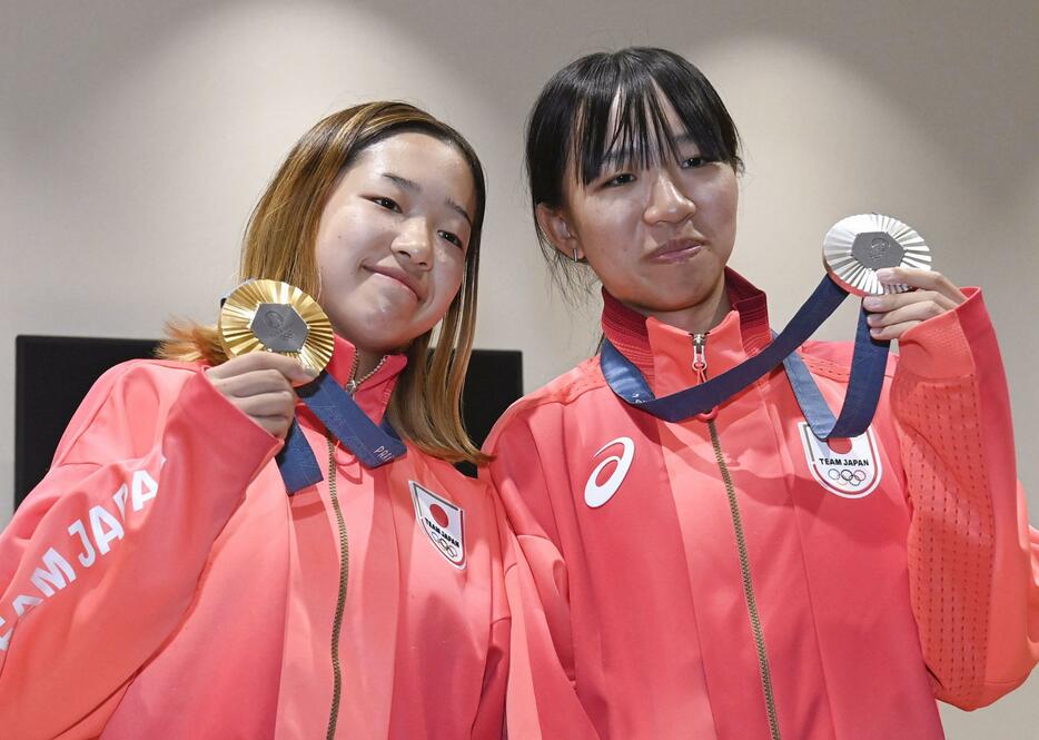 パリ五輪から帰国し、記者会見でメダルを手に笑顔を見せるスケートボード女子ストリート金の吉沢恋（左）と銀の赤間凜音＝31日午後、羽田空港