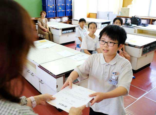 宮崎市制１００周年を記念したキッズプレスプロジェクトの委嘱状を受け取る小学生＝１９日午後、宮崎市・西池小