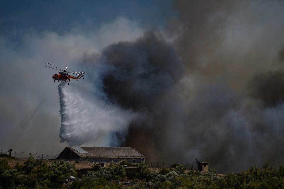 ギリシャの首都アテネ近郊のケラテアで山火事が発生し、消火活動を行う消防ヘリ（2024年6月30日撮影）。【翻訳編集】 AFPBB News