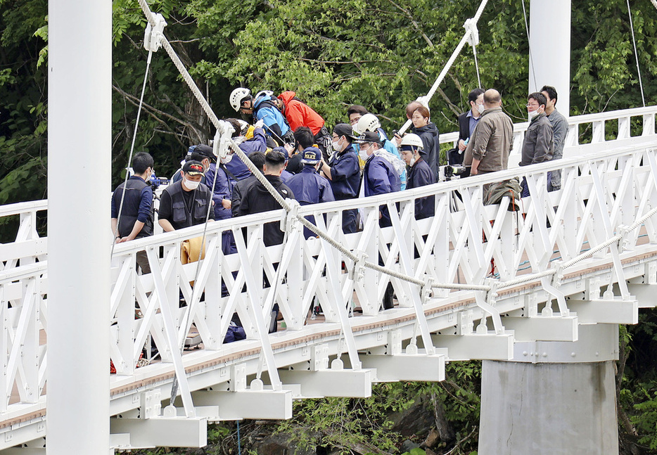 女子高校生がつり橋から川に落とされ殺害された事件の現場で実況見分する捜査員ら＝6月、北海道旭川市