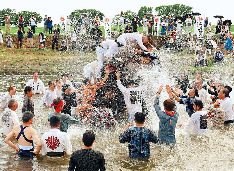 水しぶきを上げながら、神輿をもみ合う男衆＝28日、熊谷市葛和田の利根川