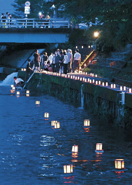 川面に浮かんだ灯籠の幻想的な光を見守る住民＝富山市清水町