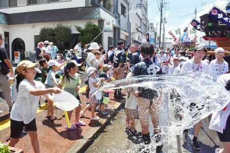 PTAが設けた水かけスポットから力水を浴びせる子どもたち＝鳥栖市の鳥栖本通筋商店街