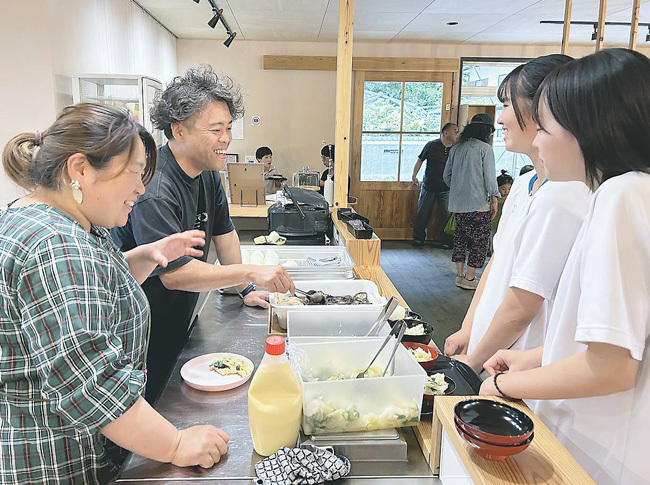 中学生にグラタンなどのメニューを説明する大岩さん（左奥）と山木さん（左）。悩みに耳を傾け、成長を見守る（徳島県佐那河内村で）