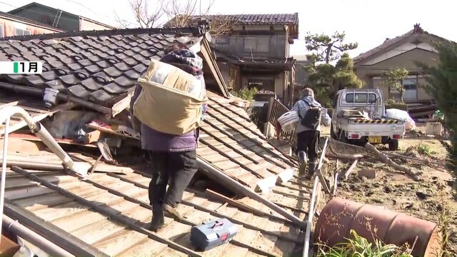 傾いた自宅から必要なものを運び出す中島さん親子