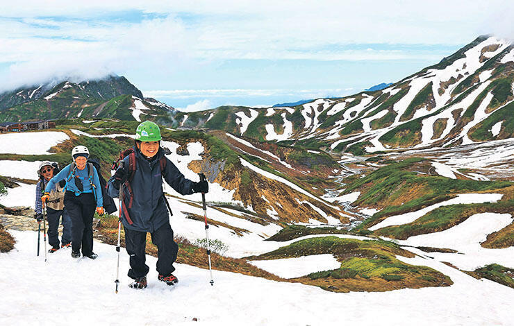 雪が残る景色を楽しみながら歩みを進める登山者=立山・室堂平