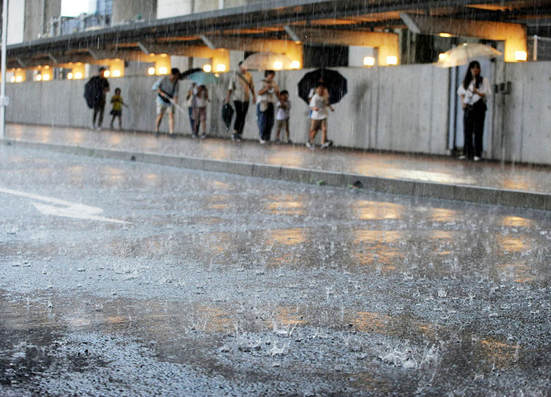 土砂降りの雨の中、駐車場から鉄道博物館に向かう人たち＝27日午後5時50分ごろ、さいたま市大宮区