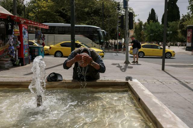 熱波が襲うギリシャ・アテネで2024年6月13日、噴水の水を浴びる男性=ロイター