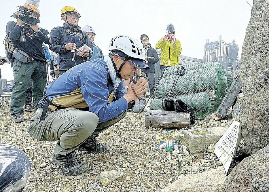 山頂で花を供え手を合わせる被災者家族