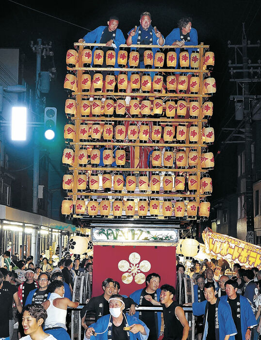 露店が並ぶ市街地を巡行する提灯山＝１３日午後８時２０分、氷見市本町