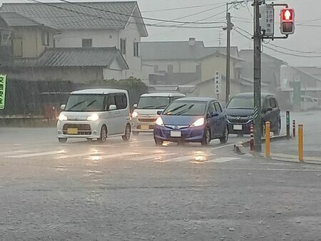 雨が強く降りだし、ライトを点灯して走行する乗用車＝14日午前9時50分ごろ、佐賀市