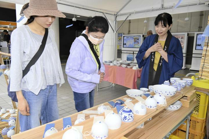 担当者（右）の説明を受けながら砥部焼を品定めする来場者