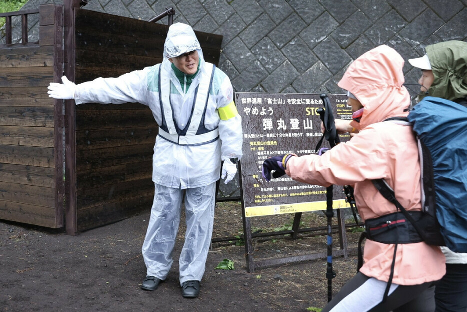 仮設ゲート前で登山客（右）のリストバンドを確認する係員＝１日午前、山梨県富士吉田市