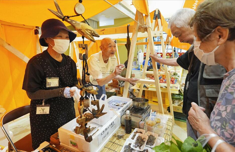 石川県輪島市内の商業施設で出張開催された輪島朝市で、川魚料理を販売する福谷春夫さん（左奥）と和子さん（同手前）夫妻＝10日午前