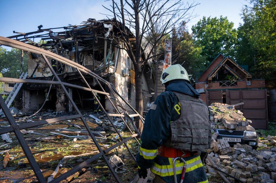 24日、ウクライナ東部ハリコフで、ロシアによる攻撃後、炎上した建物の消火活動に当たる隊員ら（ゲッティ＝共同）