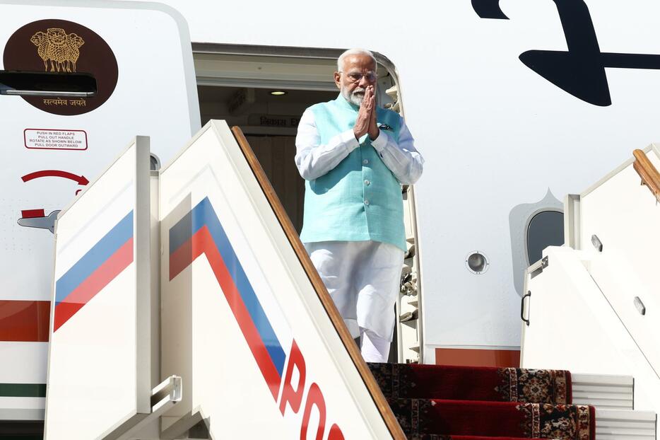 モスクワ郊外の空港に到着し、タラップで合掌するインドのモディ首相＝8日（タス＝共同）