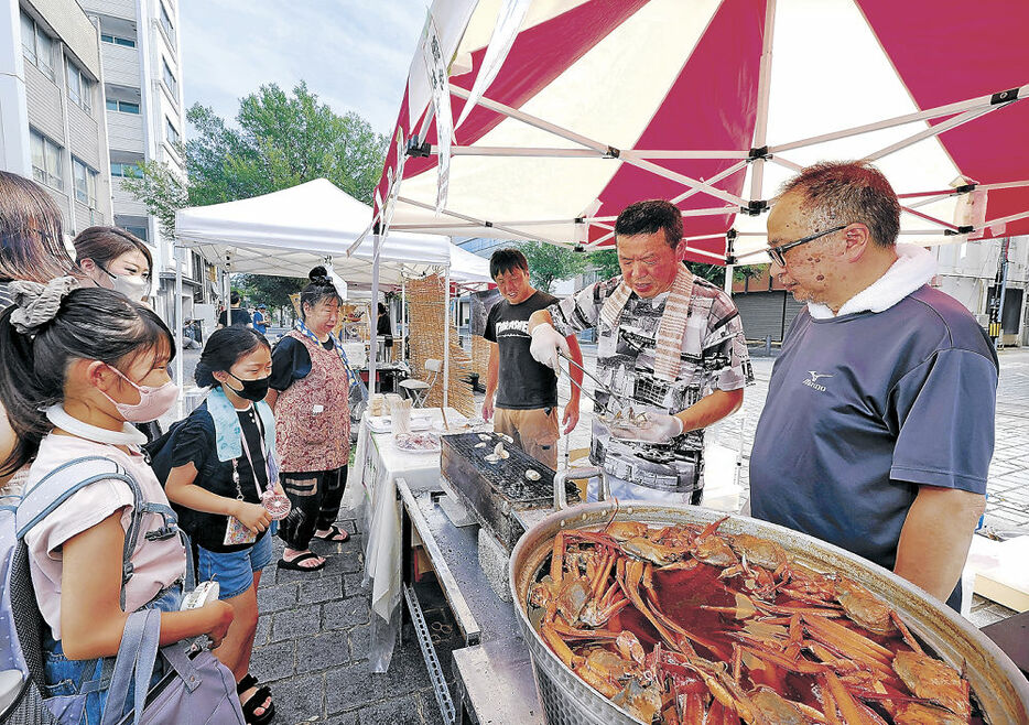 七尾で被災し、越中大手市場に初出店した「魚富」の堀さん（右手前から３人目）＝富山市の大手モール