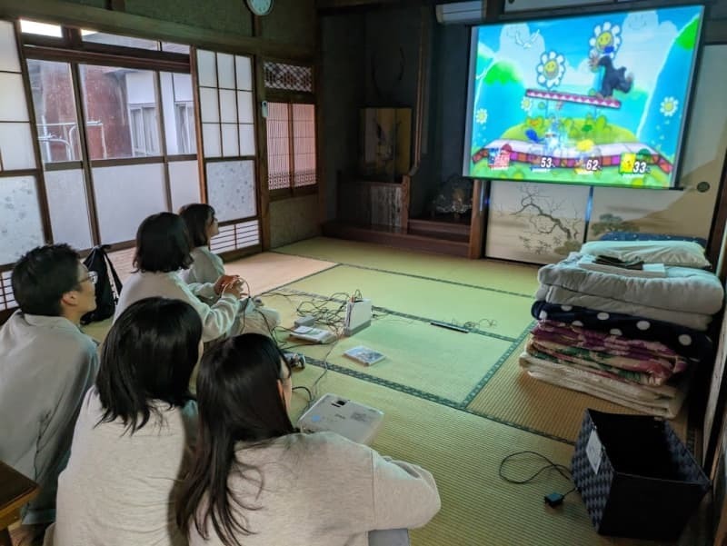 「まなかのいえ」で備え付けのテレビゲームに興じる地元の若者ら（ダイバーステイ提供）