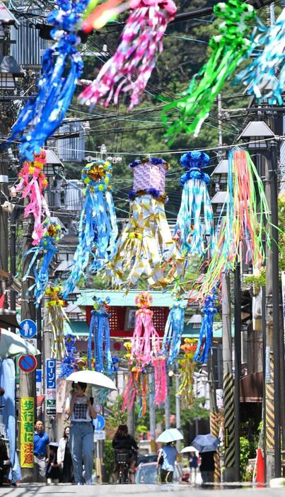 七夕飾りで彩られた商店街で、日傘を差して歩く人たち。地面には「逃げ水」現象も＝４日午前、神戸市須磨区の須磨寺前商店街（撮影・風斗雅博）