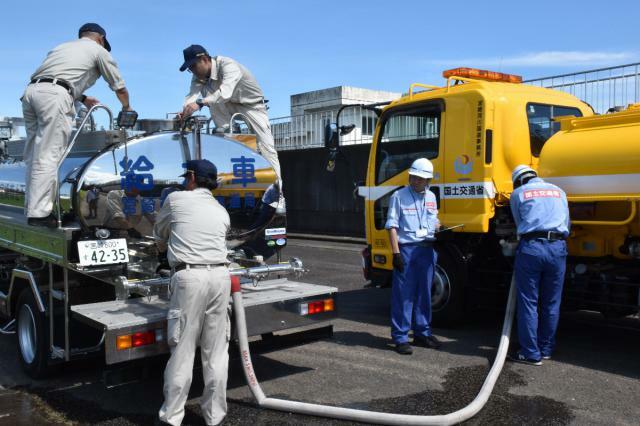 散水車から給水車に水を補水する両機関の職員