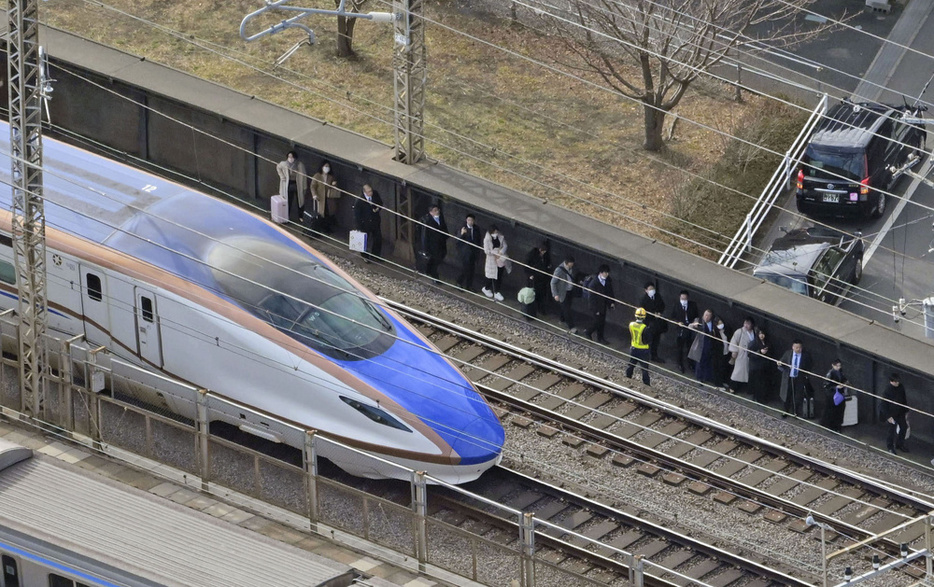 1月、さいたま市中央区で停車した新幹線から降り、線路脇を歩く人たち