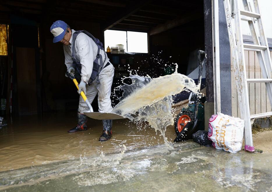 浸水した山形県戸沢村の古口地区で、倉庫から水をかき出す男性＝27日午前9時58分