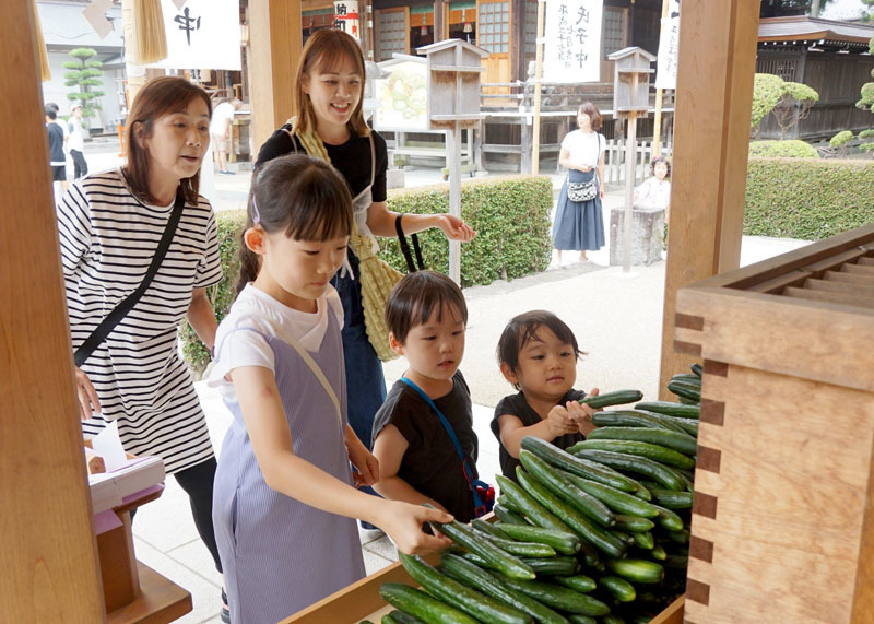 家族の安寧を願い、キュウリを奉納する子どもたち