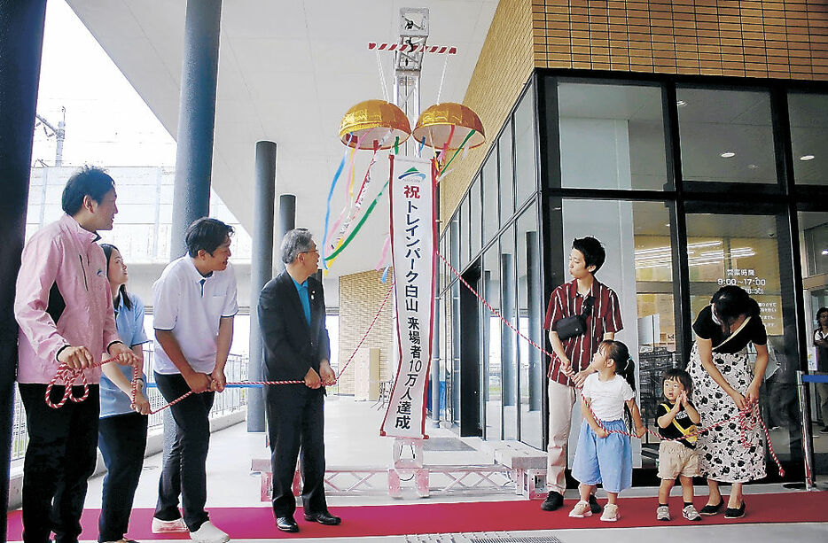 くす玉を割る高出さん家族（右）＝白山市立高速鉄道ビジターセンター