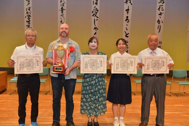 （写真右から）審査員特別賞の川満さん、文化協会長賞の西銘さん、市長賞の園江さん・マイケルさん夫妻、教育長賞の友利さん＝14日、マティダ市民劇場