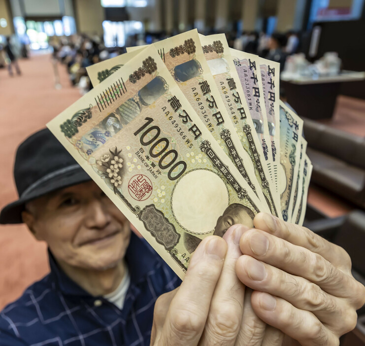 新しい紙幣（日本銀行券）３券種の流通が３日、始まった。デザインの変更は約２０年ぶり。写真は、新紙幣を手にする人＝東京都千代田区
