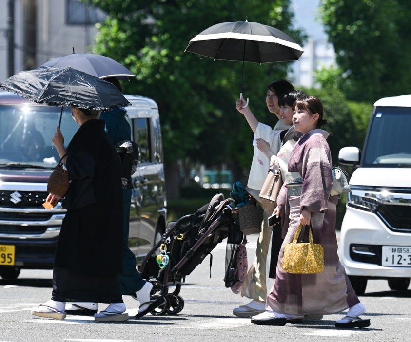 厳しい暑さと強い日差しの中、日傘を差して歩く着物姿の女性たち＝4日午前11時15分、静岡市駿河区