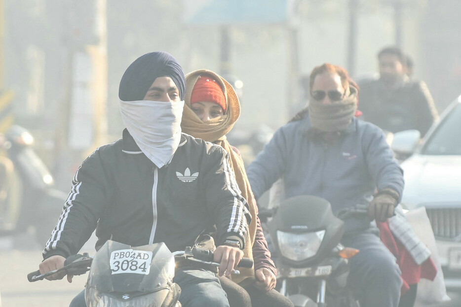 インドの研究チームは４日、同国では大都市の死因の７．２％が大気汚染に関連しているとの調査結果を発表した。写真は大気汚染の中、布で顔を覆い通勤する人々＝２０２３年１２月撮影、北部アムリトサル