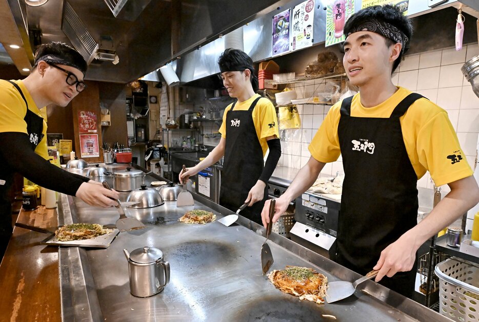 五エ門の胡町本店でお好み焼きを焼くナムさん㊨たち外国人