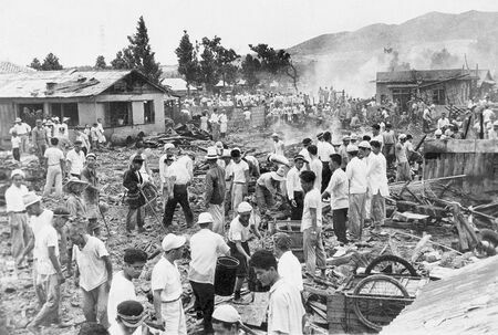 米軍戦闘機の墜落で６区公民館と民家２７棟が焼失し、消火活動にあたる住民ら＝１９５９年６月３０日、うるま市石川