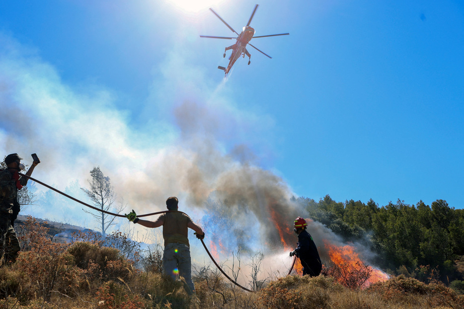 　ギリシャのミツォタキス首相は７月１日の閣議で、今夏は国内で森林火災が多発する恐れがあると懸念を示した。干ばつの長期化と異常な強風が火種になる可能性があるという。写真はヘリコプターを利用した消火活動の様子。６月３０日、アテネ近郊で撮影（２０２４年　ロイター/Elias Marcou）