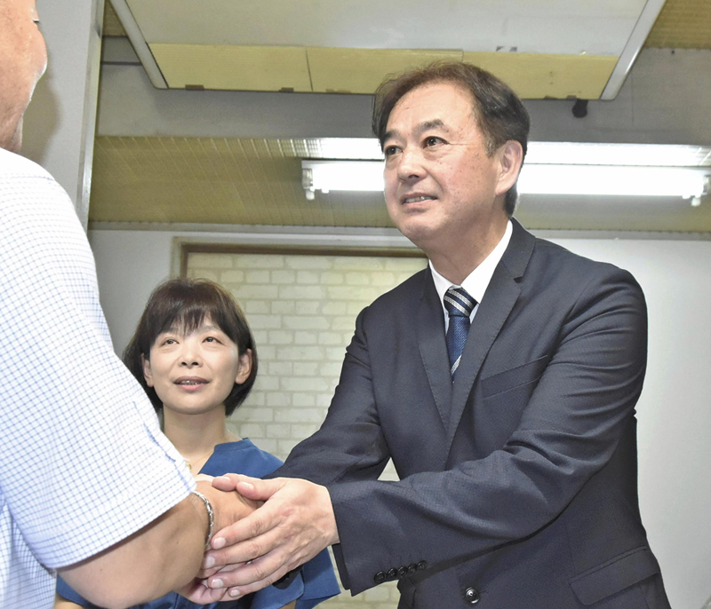 初当選し、支持者と握手を交わす首藤氏（右）と妻亜希子さん＝30日午後9時半ごろ、石川町