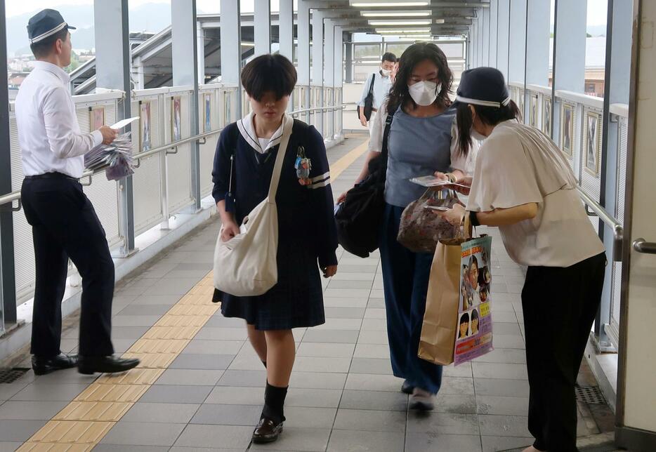 吉川友梨さんの情報提供を求めてJR熊取駅前でチラシを配る大阪府警の捜査員ら＝2日午前