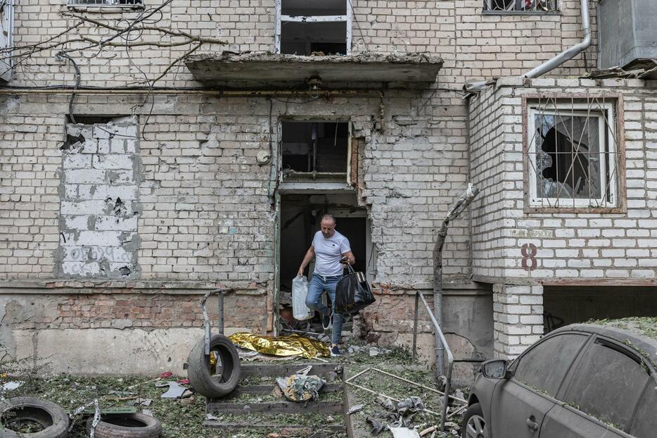 ロシア軍による砲撃で壊れた建物から所持品を持って出る男性＝19日、ウクライナ南部ミコライウ（ゲッティ＝共同）