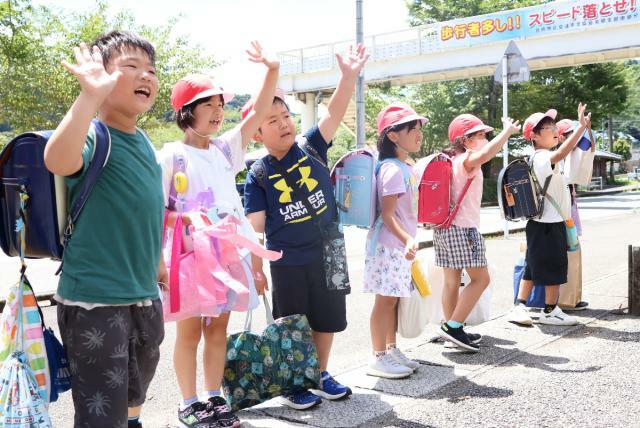 夏休み前最後の学校を終え、見送る先生たちに手を振る美郷南学園の子どもたち＝１９日午後、美郷町南郷