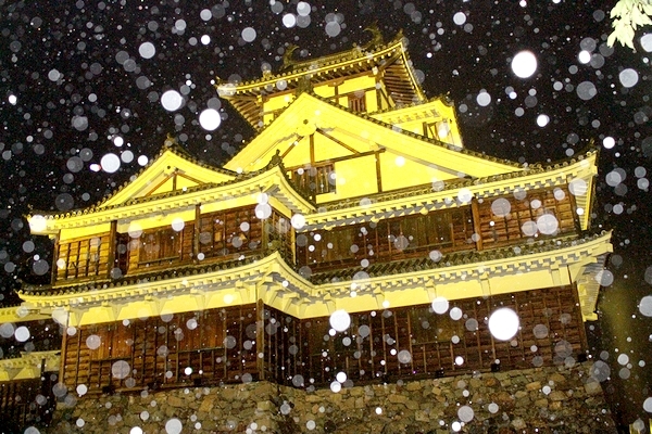 雨の中、黄色にライトアップされた福知山城