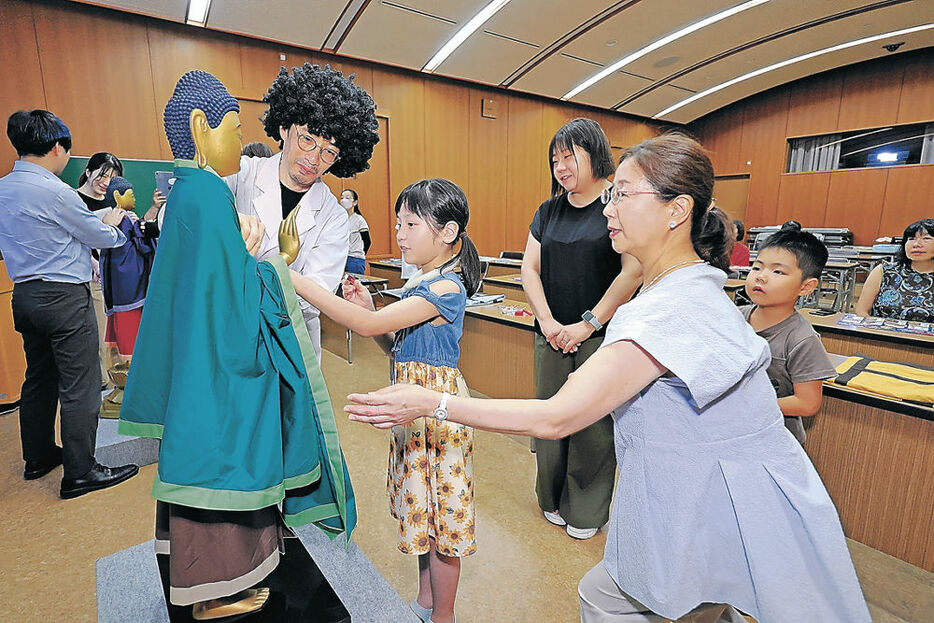 仏像ハカセと仏像の「着付け」を体験する親子＝金沢市の石川県立美術館