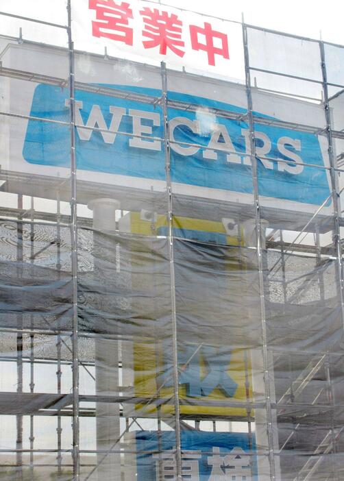 かけ替え工事が進む「WECARS（ウィーカーズ）」が設置した新会社名の看板＝24日午前、東京都多摩市