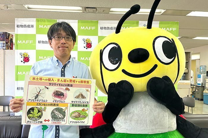 植物などの移動規制の周知をする那覇植物防疫事務所の佐久本統さん（左）とぴーきゅん＝4日、那覇市の県庁