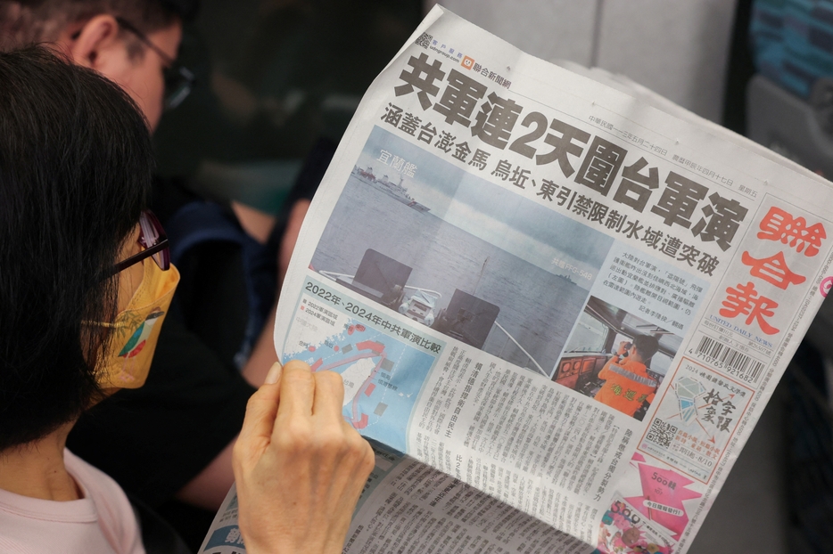 [写真]台湾周辺で中国軍が軍事演習を開始したことを伝える新聞を読む女性（ロイター/アフロ）