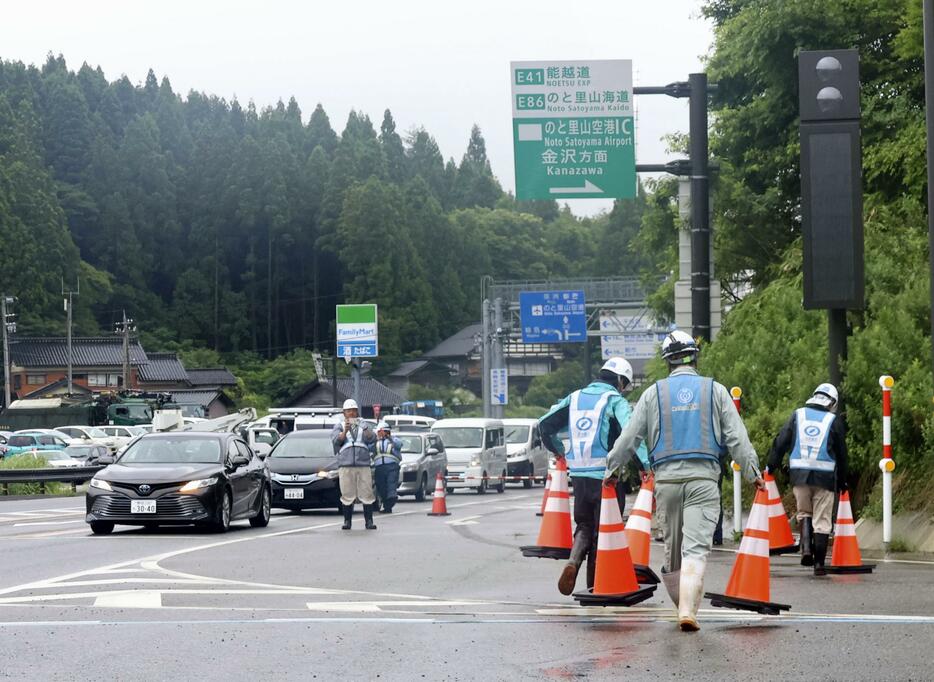 のと里山空港インターチェンジで、通行止めの三角コーンを撤去する作業員ら＝17日正午ごろ、石川県輪島市