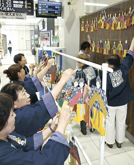 松本駅の改札口に七夕人形を飾り付ける会員たち