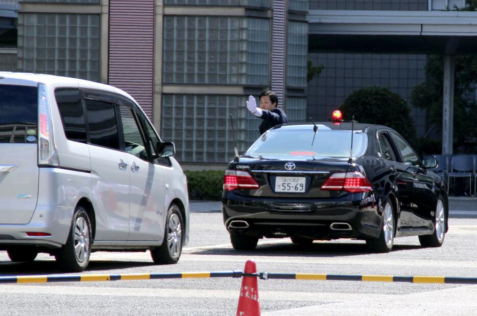 警視庁が警察学校で開いた採用イベントで、警護車から身を乗り出して一般車両の接近を制止するSP＝26日午前、東京都府中市