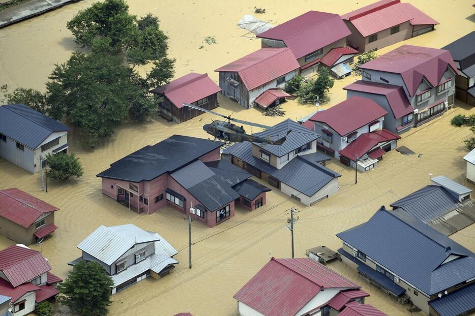 大雨の影響で浸水した山形県戸沢村の住宅を捜索する自衛隊のヘリ＝26日午前10時36分（共同通信社機から）