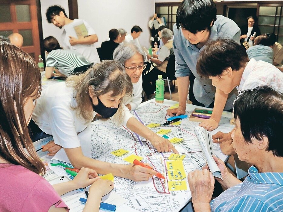 拡大した住宅地図に被災箇所を書き込む学生と住民＝新島公民館